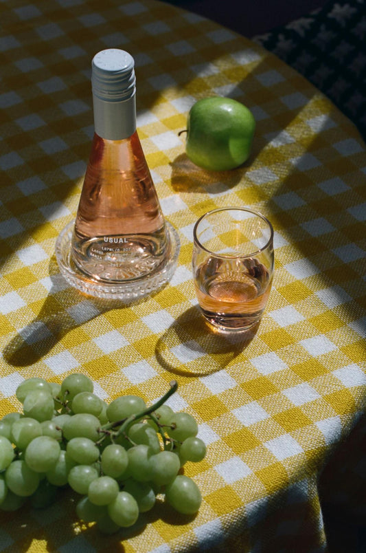 white wine glasses: Usual Wines bottle, an apple and grapes on the table