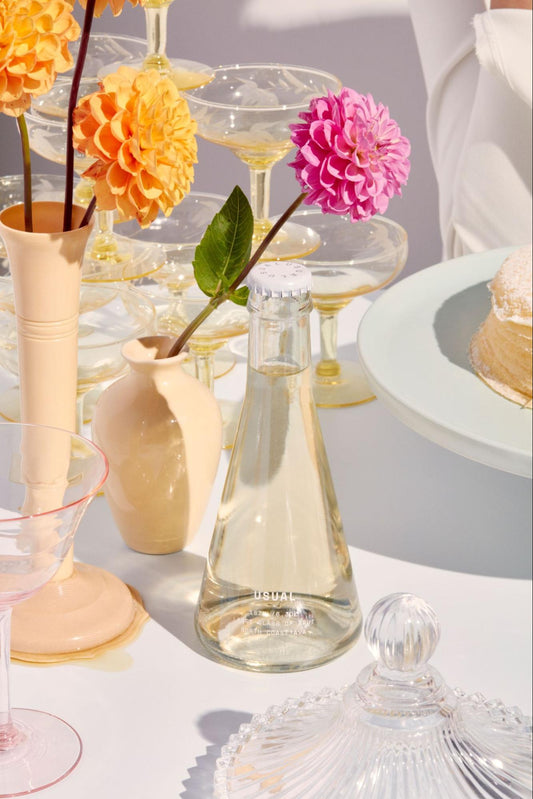 is Chardonnay dry: large bottle of Usual Wines Brut on a table with pink and yellow flowers