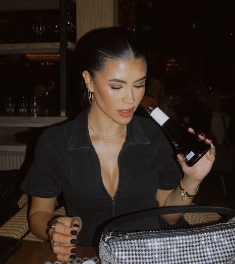 Image of a young woman drinking usual wines by the bottle in a modern restaurant