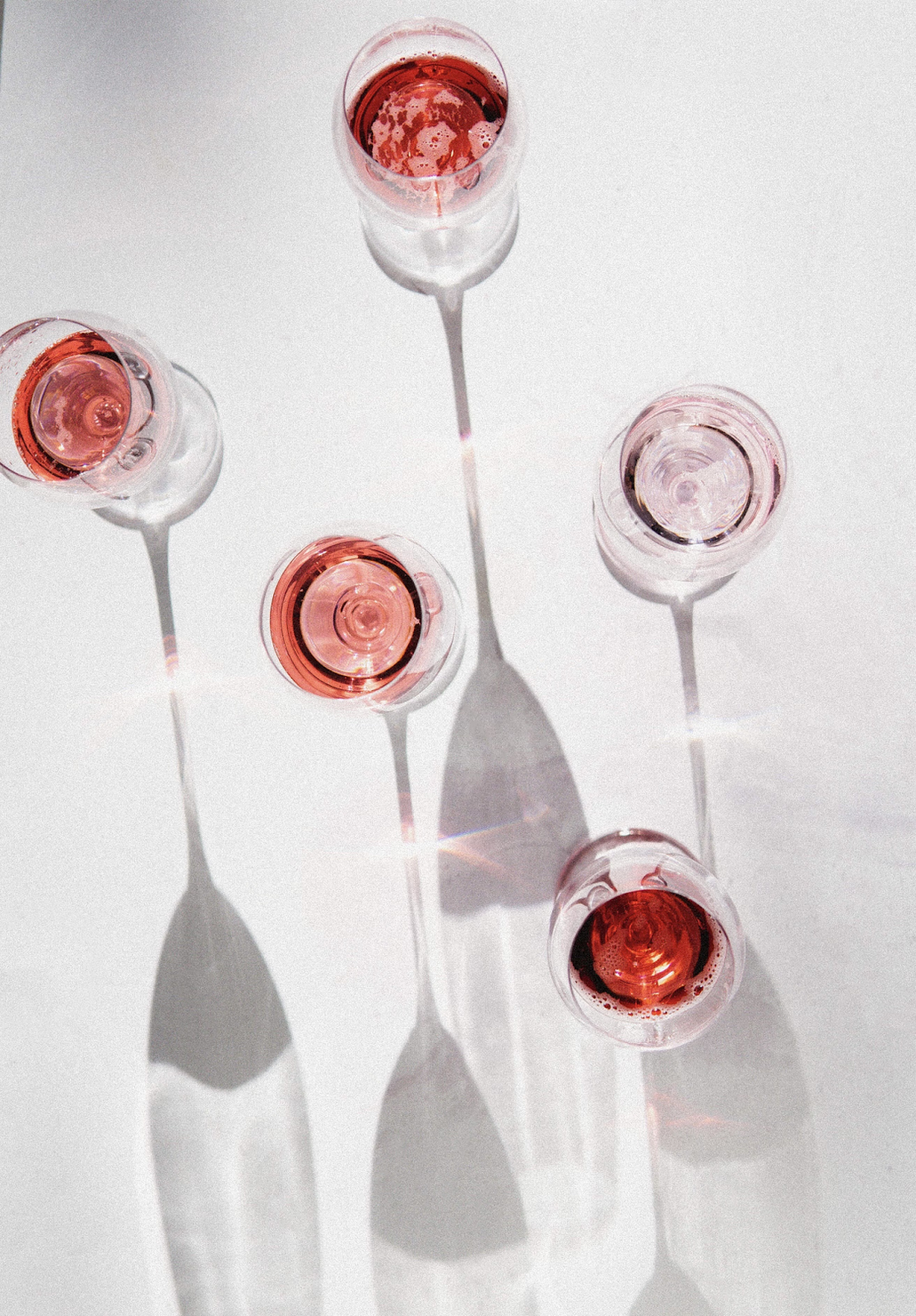 Image of rose wine in sparkling glasses, on white background with shadows 