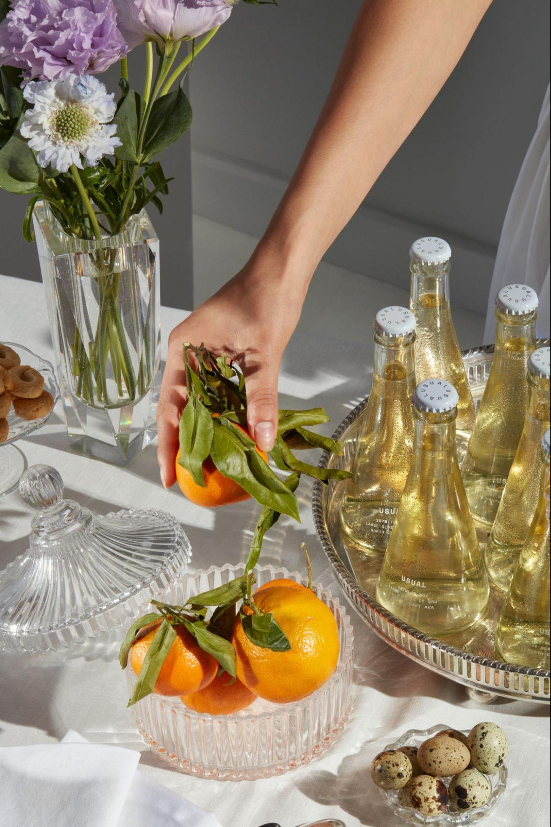 Muscat wine: person holding an orange with several bottles of Brut from Usual Wines on a silver platter