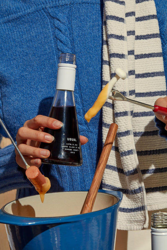 Cooking wine: Person holds Usual Wines bottle while dipping fondue